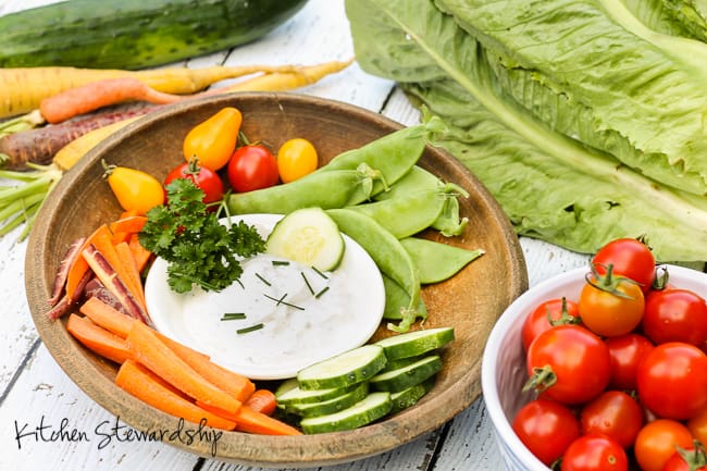 Homemade ranch dressing and raw veggies on a wooden plank table. 