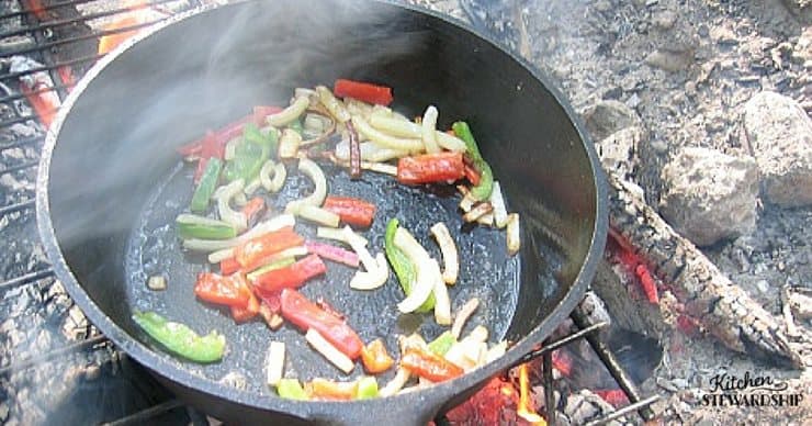 Vegetables sauteing in a cast iron skillet over a camp fire, easy camping food