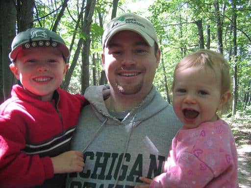 Dad holding young boy and toddler girl, all smiling.