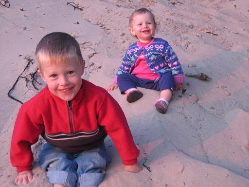 Young boy and toddler girl in the sand.