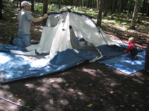 Man and toddler setting up a tent for camping
