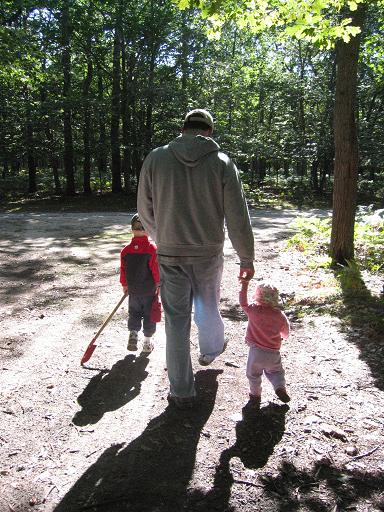 Dad, toddler and young boy walking in the woods