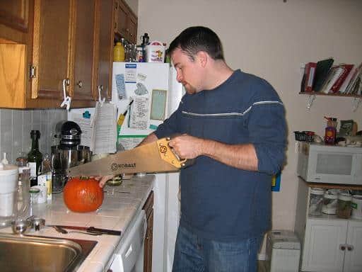 cutting open a pumpkin with a saw