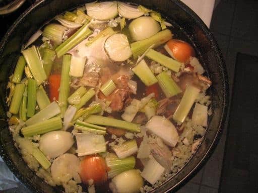 Looking down at a stock pot filled with water, meat, and veggies