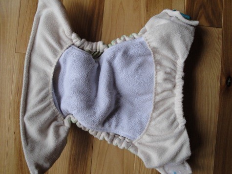 An open cloth diaper on a wooden table 0 tuck and go cloth diaper