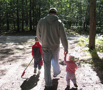 A man walking in the woods with two small children