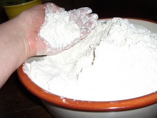 Hand scooping flour out of a large bowl