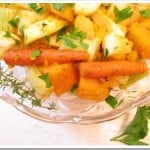 Roasted root vegetables on a glass plate garnished with herbs