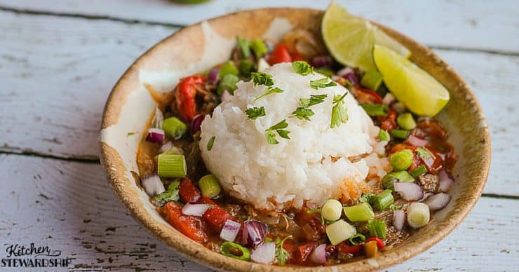 A bowl of gazpacho with rice garnished with lime and cilantro