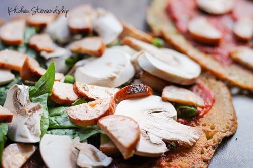 Chickpea pizza crust with all the toppings - tomato sauce, spinach, and mushrooms