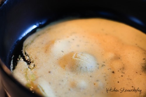 Chickpea flour pizza crust batter cooking in a cast iron pan.