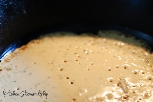 Garbanzo bean flour pizza crust cooking in a cast iron pan - bubbling like pancakes