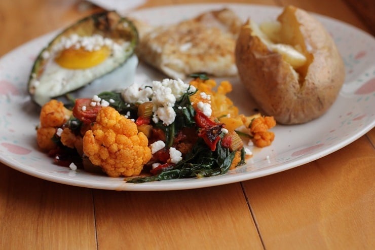 Egg in Avocado with Baked Potato and Sauteed celery red pepper cauliflower tomatoes and spinach