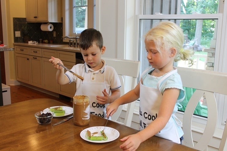 Two young kids making ants on a log.