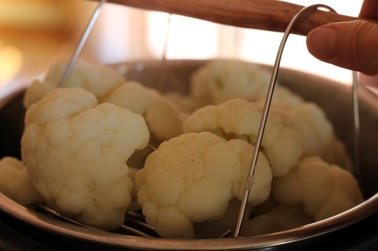 Instant Pot steaming tray lifting cauliflower out of stainless steel insert.