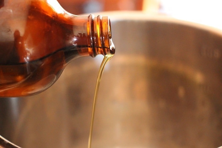 Oil from an amber colored bottle being drizzled into an Instant Pot