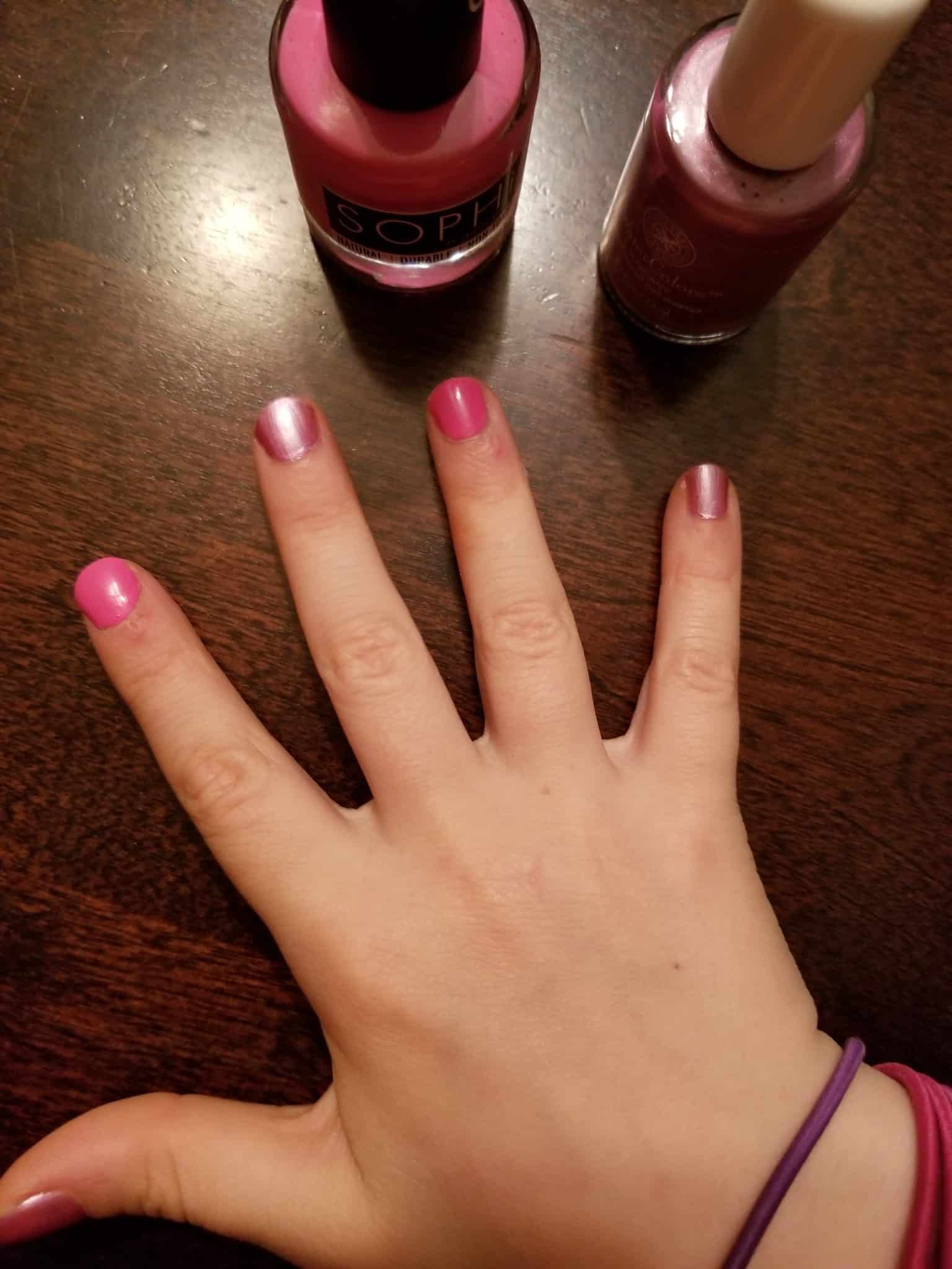 A close up of a hand with pink fingernail polish