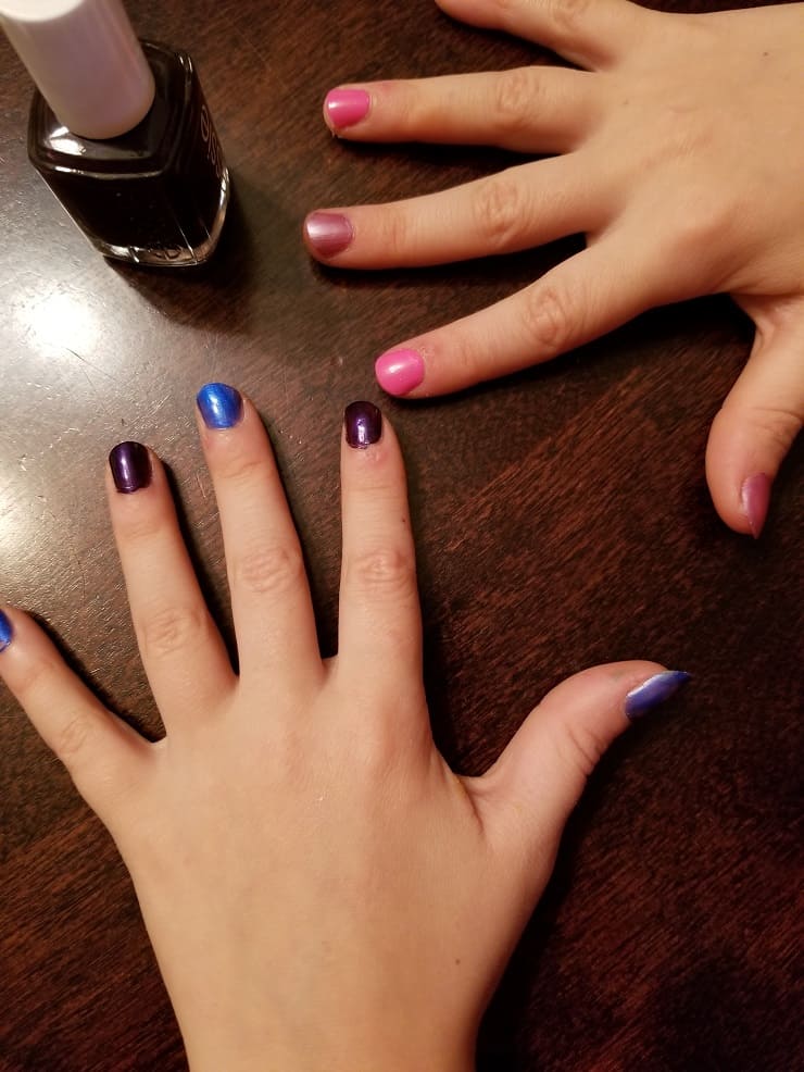 A close up of a hand with blue and purple fingernail polish