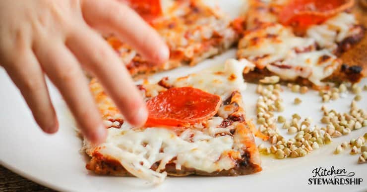 Grabbing a piece of freshly baked einkorn pizza with a crispy crust. 