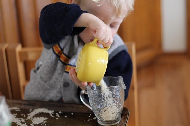 preschool boy pouring rice to learn small motor skills