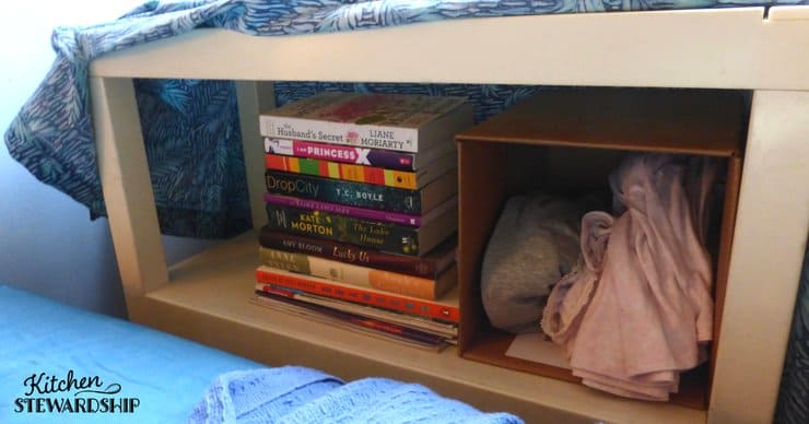 Using shelves for a bedside table and covering with fabric to keep things looking tidy.