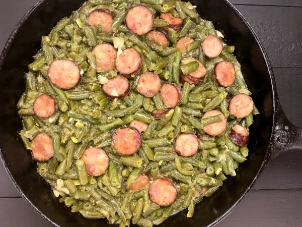 green beans and sausage in a cast iron pan