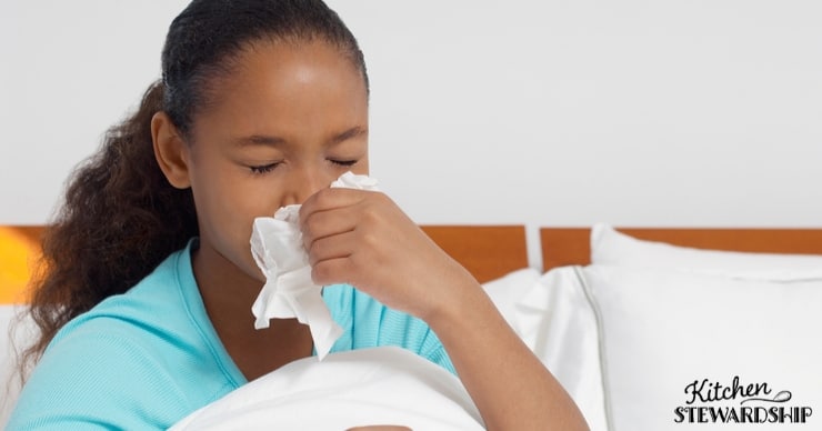 girl sneezing into tissue