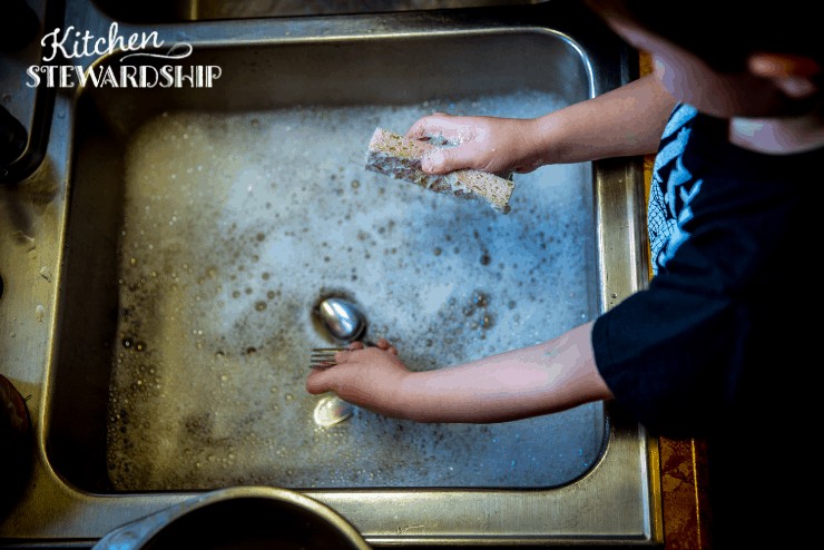 child washing the dishes with non antibacterial soap and sponge