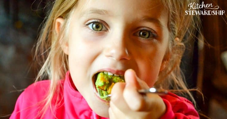 Young girl eating a healthy snack with guacamole