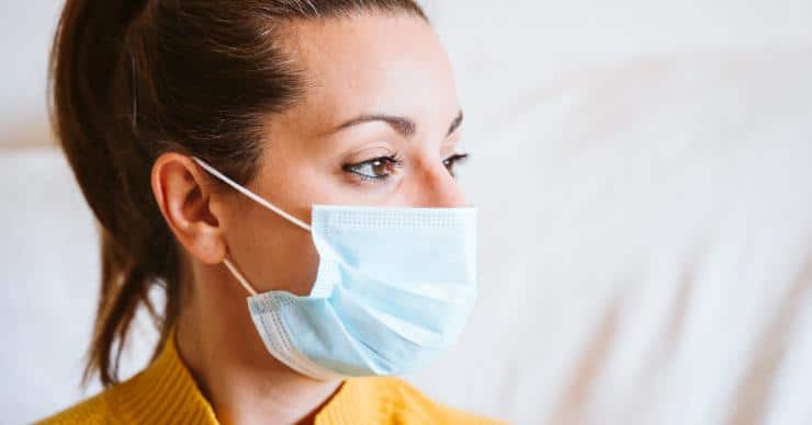 A woman wearing a surgical mask to protect herself against potential indoor air pollutants like dust and germs.