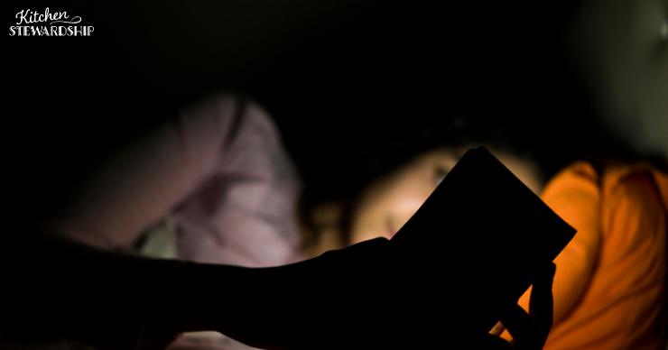 Woman with insomnia using her cell phone while lying awake at night