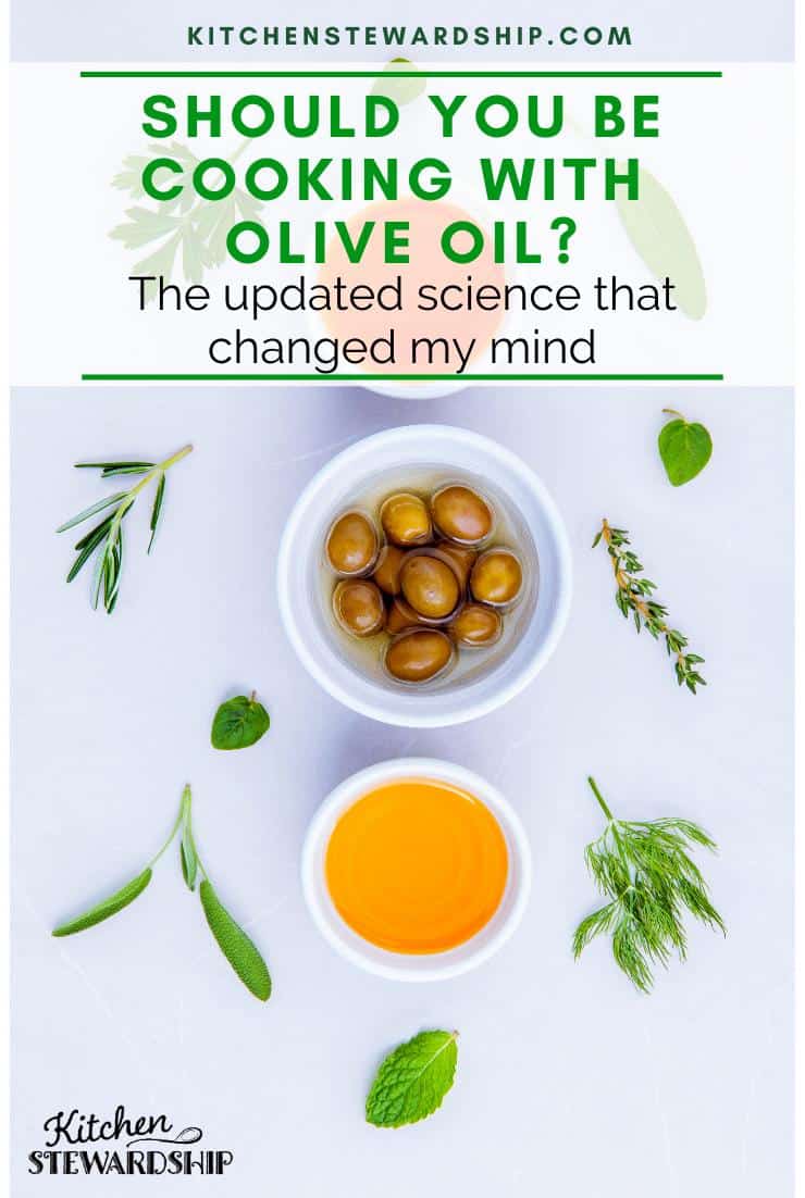 Bowl of olives and 2 bowls of olive oil on a white table with herbs. Should you be cooking with olive oil? The updated science that changed my mind.