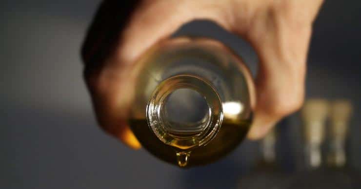 Hand holding a bottle of olive oil ready to pour