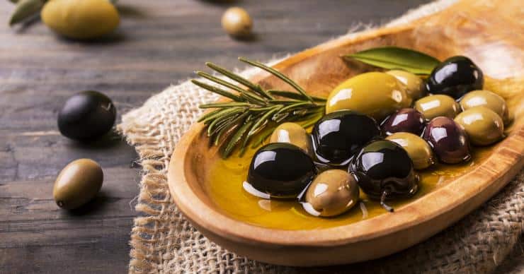 Olives, rosemary, and olive oil in a wooden spoon