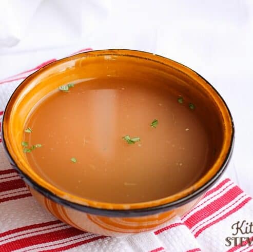 bowl of homemade chicken stock on a red striped hand towel