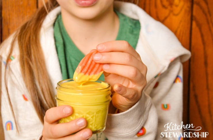 girl dipping a carrot in honey mustard dressing